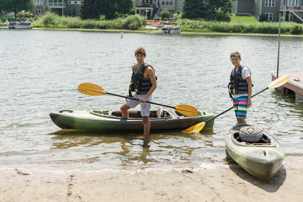 Boys with kayaks on lake 